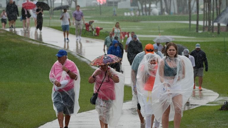 Spectators exit the course as heavy rain delays the final...