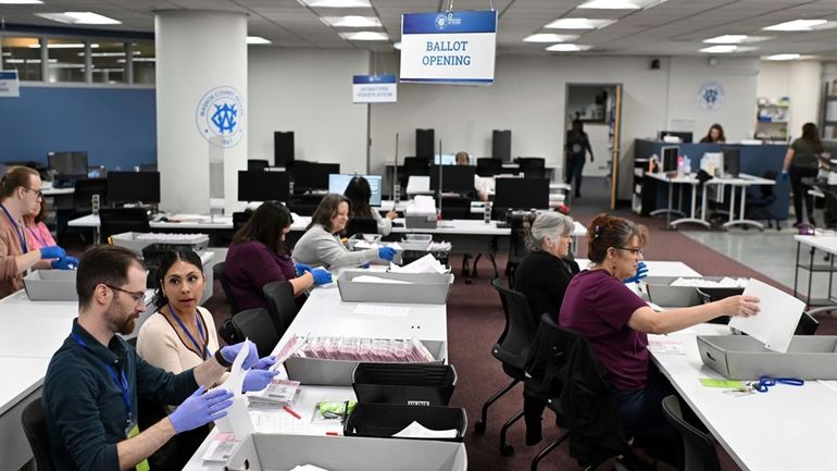 County employees open ballots in the ballot opening area of...