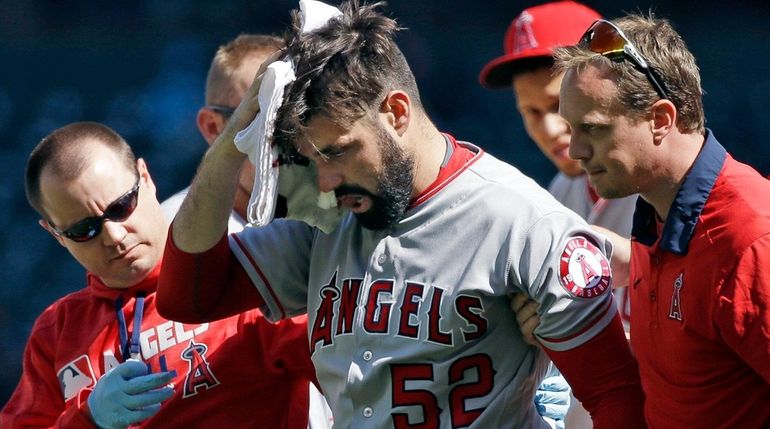 Los Angeles Angels starting pitcher Matt Shoemaker is assisted off...