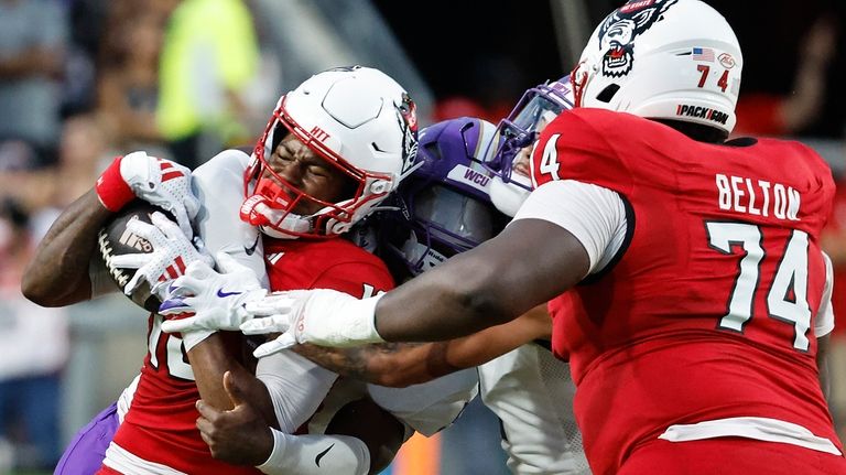 North Carolina State wide receiver Kevin Concepcion (10) gets tied...