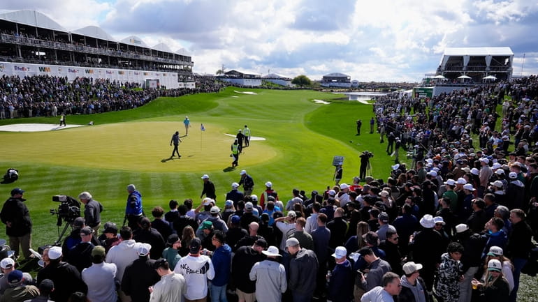 Golfers survey the 18th green as thousands in the gallery...
