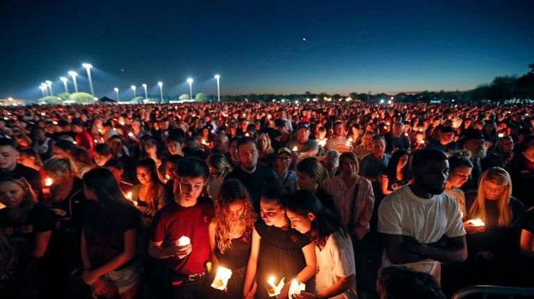 People attend a candlelight vigil for the victims of the...