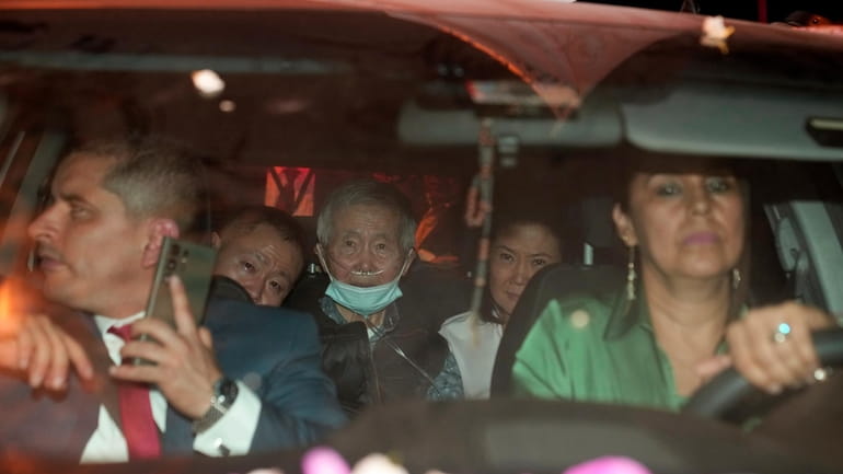 Peru's former President Alberto Fujimori, 85, center, is driven out...