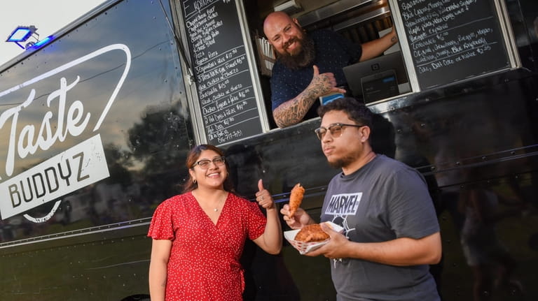 Jose Portillo of Tasty Budz food truck serves empanadas to...