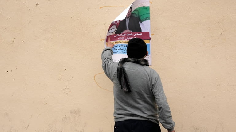 A man looks at an electoral poster of Hamid Abdolmaleki,...