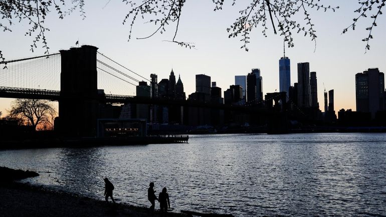 People walk along the East River at Main Street Park,...