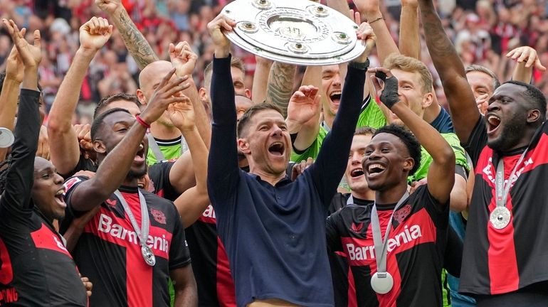 Leverkusen's head coach Xabi Alonso celebrates with the trophy as...