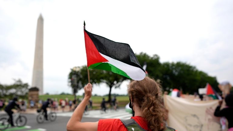 A demonstrator waves a Palestinian flag near the Washington Monument...