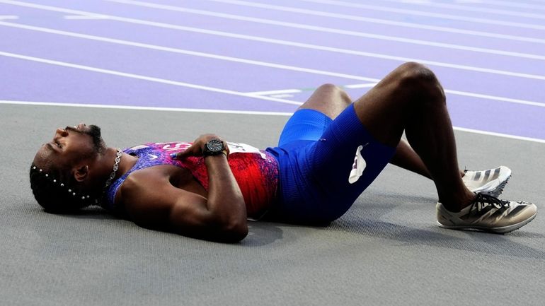 Noah Lyles, of the United States, lies on the track...