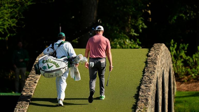 Jon Rahm, of Spain, walks over the bridge on the...