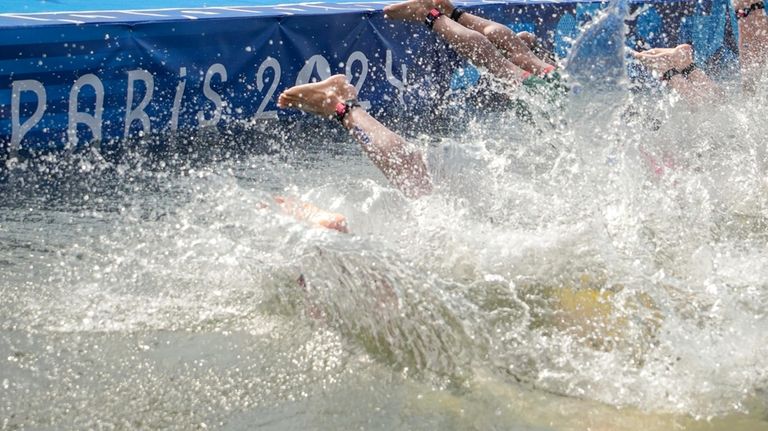 Athletes dive into the water for the start of the...