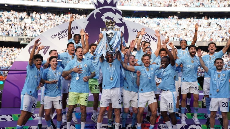 Manchester City players celebrate with the Premier League trophy after...