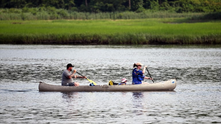 A family navigates their canoe along the Nissequogue River in...
