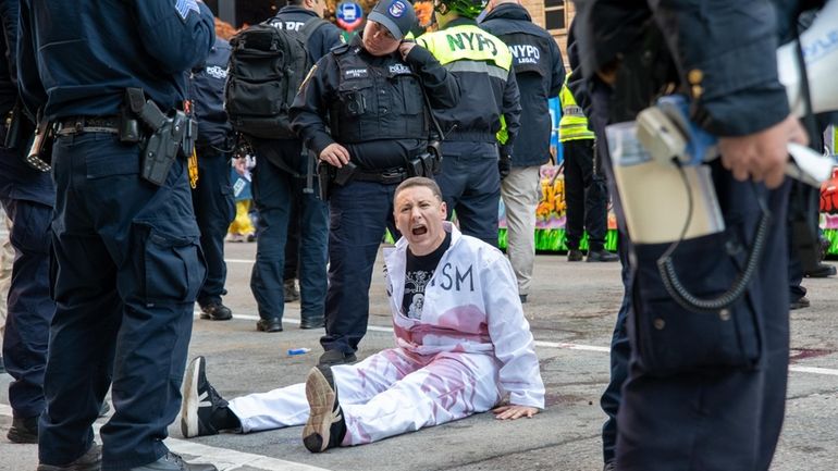 A protester with hands glued to the street at the...