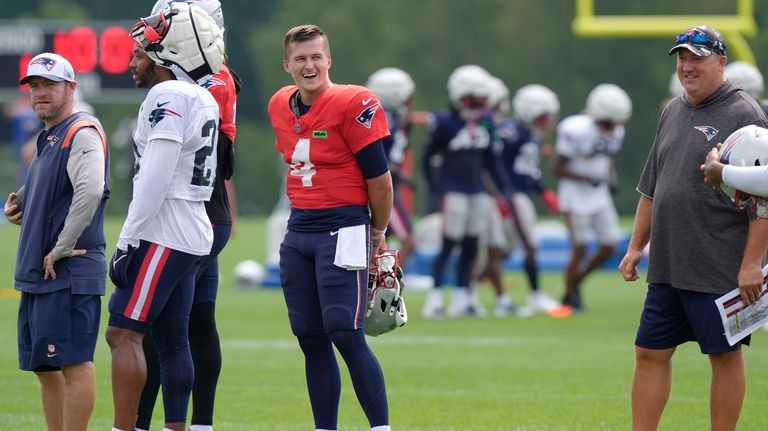 New England Patriots quarterback Bailey Zappe (4) smiles while standing...