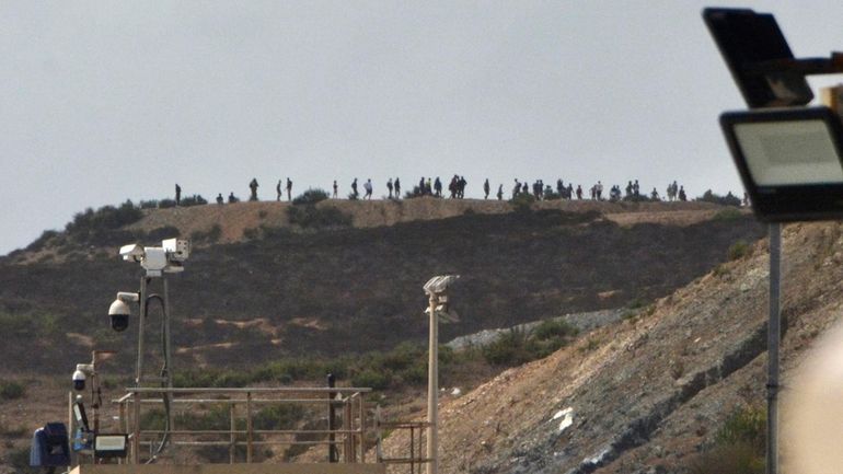 People thought to be migrants stand on top of hill...