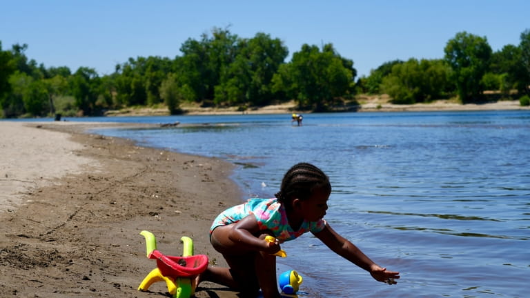 A young girl plays on the sand by the river...