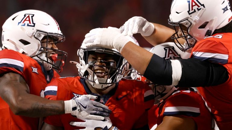 Arizona running back Kedrick Reescano (3) gets mobbed by his...