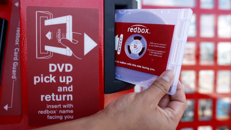 A rental DVD is dispensed from a Redbox at a...