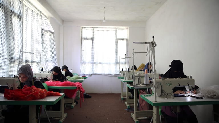 Afghan women tailors work with a sewing machine in the...