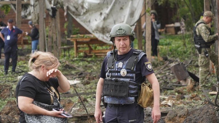 A woman cries as police officers inspect the site of...