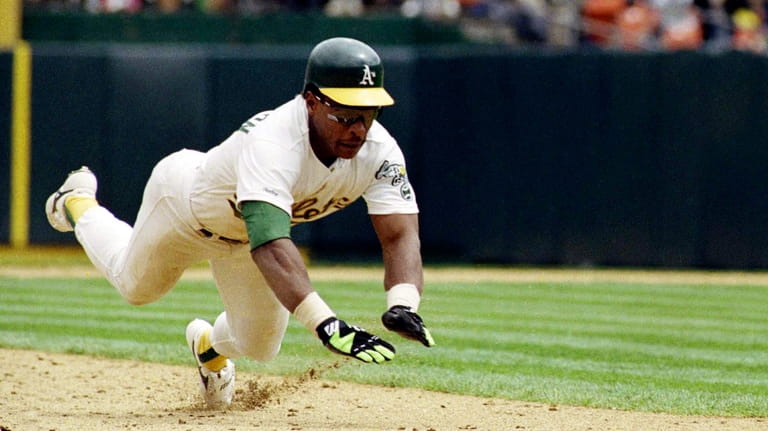 Oakland Athletics' Rickey Henderson dives for third base to steal...