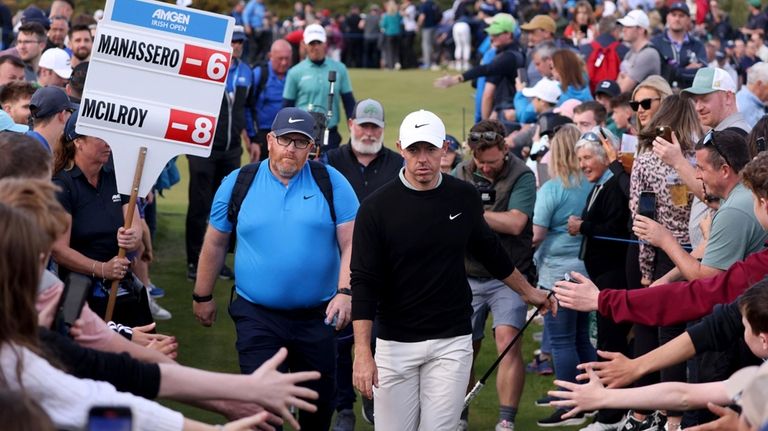 Northern Ireland's Rory McIlroy walks between lines of fans as...