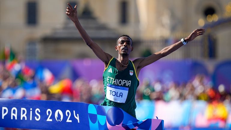 Ethiopia's Tamirat Tola celebrates after crossing the finish line to...