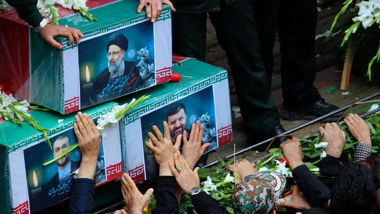 In this photo provided by Fars News Agency, mourners try...