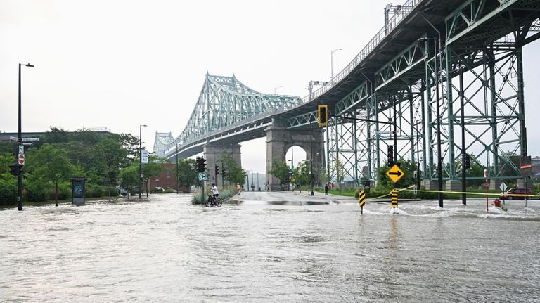 A flooded street is shown due to a broken water...