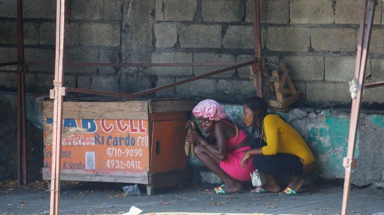 Women take cover during a gun battle between police and...