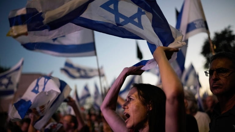 People wave Israeli flags during a protest against Israeli Prime...
