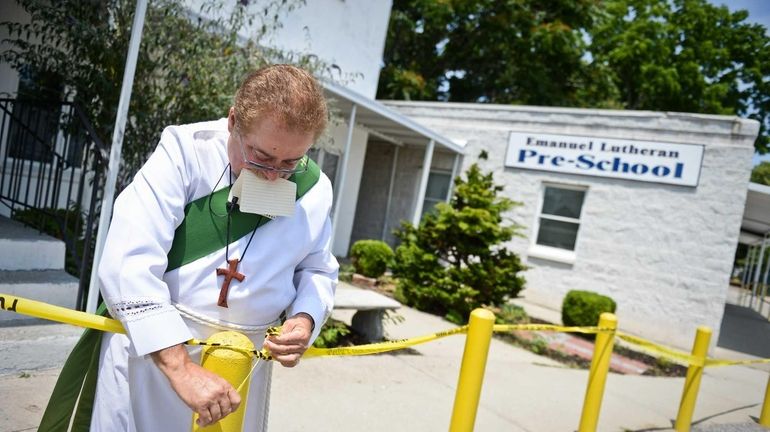 Deacon John Gallaer ties up crime scene tape that had...