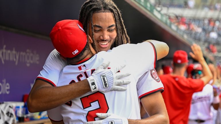 Washington Nationals' James Wood, right, is embraced by Nationals' Luis...