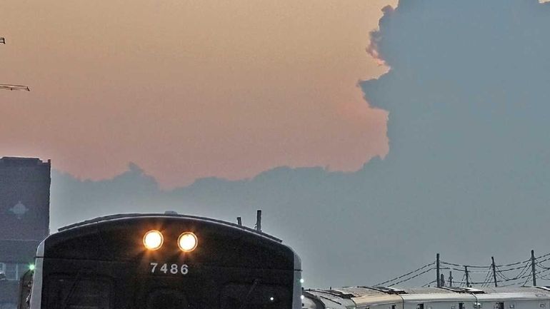 Eastbound LIRR train enters Jamaica station with storm clouds over...