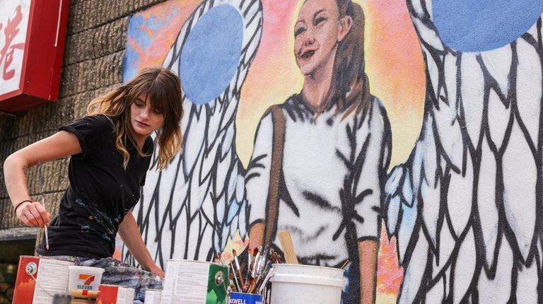 Tess Parker, an artist from East Islip, paints a mural in...