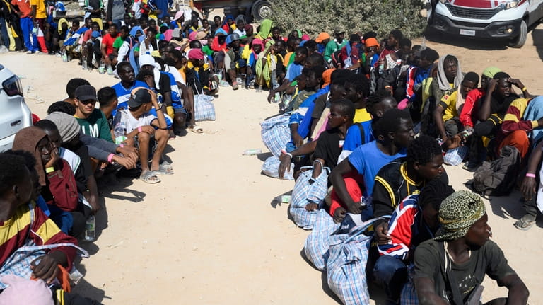 Migrants sit outside the Lampedusa's migrant reception center, Sicily, Thursday,...