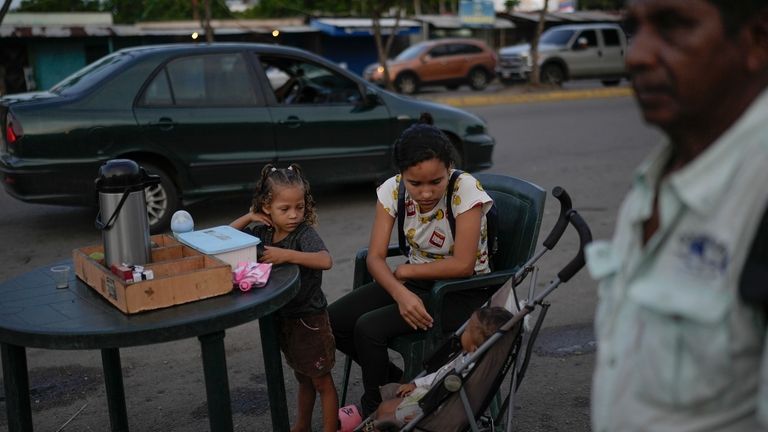 A woman with her children sells coffee near a bus...