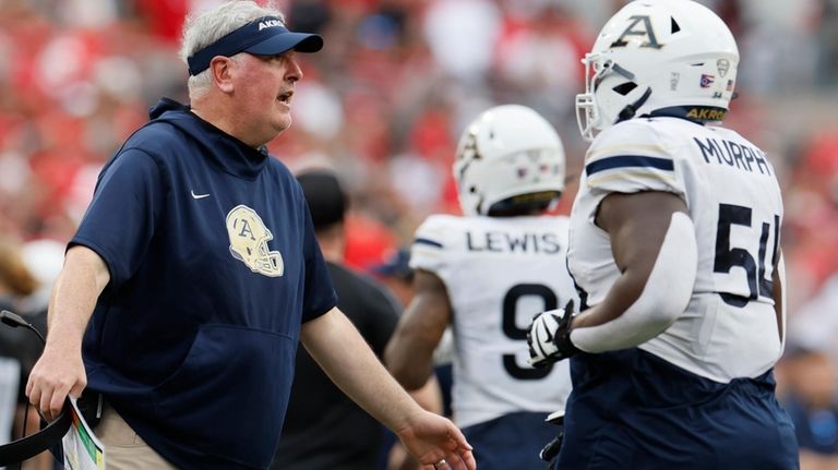 Akron Head coach Joe Moorhead, left, talks to players during...