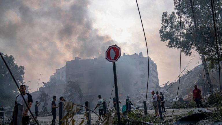 Palestinians inspect the rubble of a building after it was...