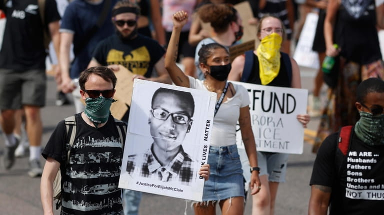 Demonstrators carry placards as they walk down Sable Boulevard during...