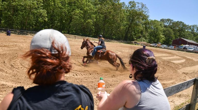 A rider circles one of the barrels while spectators look...