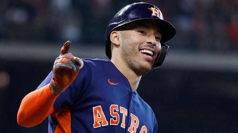 The Astros' Carlos Correa celebrates after driving a solo home...