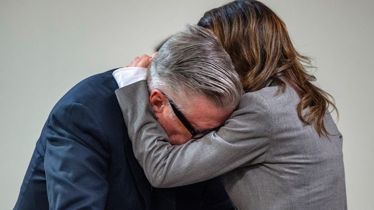 Actor Alec Baldwin, left, reacts as his wife Hilaria hugs...