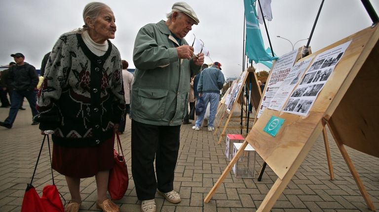 Belarusians read posters during an anti-election campaign picket in Minsk,...