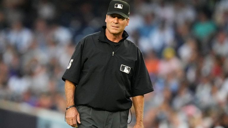 Umpire Ángel Hernández looks on during the first inning of...