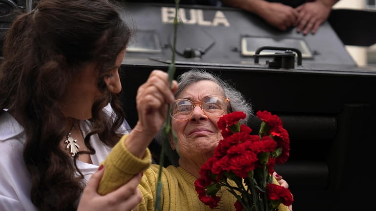 Celeste Caeiro, 90, holds a bunch of red carnations, in...