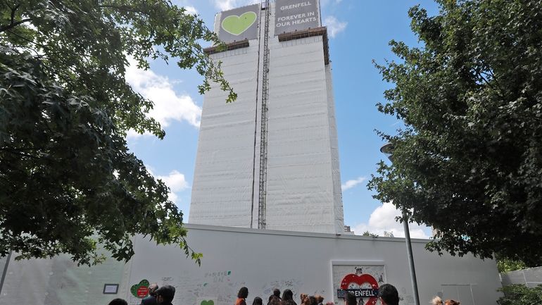 People pay their respects at the Grenfell tower to mark...