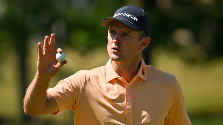 Justin Rose, of England, waves after making a putt on...