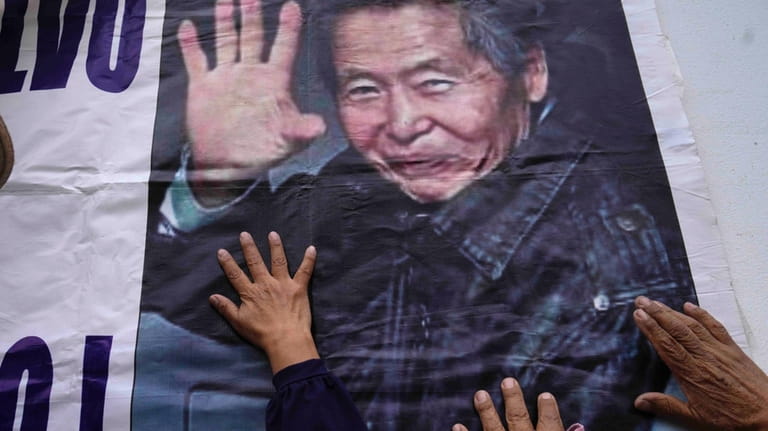 Supporters of jailed former president Alberto Fujimori touch a sign...